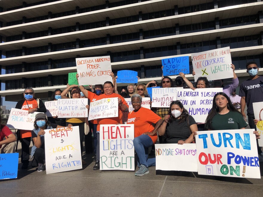 A group of people holding signs asking to stop energy cutoffs poses for a photo.