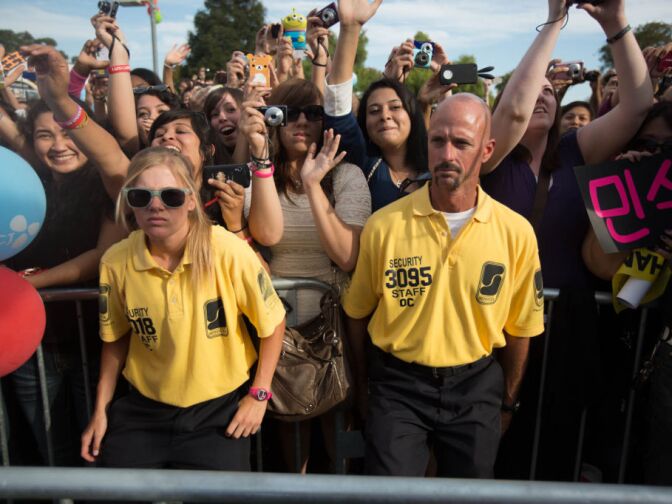 Security guards hold back a barrier against surging fans at KCON, the United States' first convention for Korean pop music, at the Verizon Ampitheatre in Irvine, Calif.