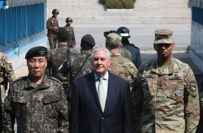 US Secretary of State Rex Tillerson (C) poses for a photograph with US Gen. Vincent K. Brooks (R), commander of the United Nations Command, Combined Forces Command and United States Forces Korea, and deputy Commander of the Combined Force Command General Leem Ho-young (L) as two North Korean soldiers (top) look on at the border village of Panmunjom, which has separated the two Koreas since the Korean War, on March 17, 2017.
Washington's top diplomat visited the Demilitarised Zone dividing the two Koreas to gaze on the North for himself on March 17, a day after he declared 20 years of efforts to denuclearise it had failed.  / AFP PHOTO / POOL / Lee Jin-man        (Photo credit should read LEE JIN-MAN/AFP/Getty Images)