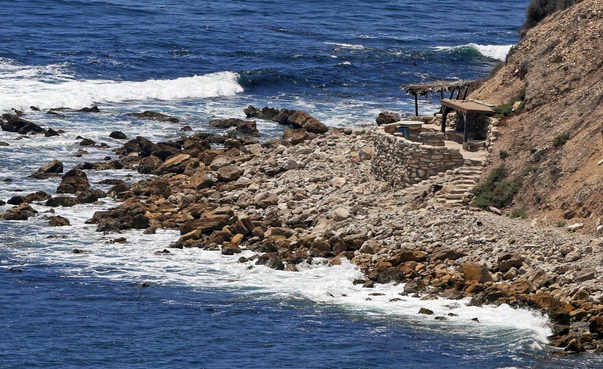 This July 12, 2016, photo shows a stone structure at Rocky Point in Lunada Bay in the tiny, seaside city of Palos Verdes Estates, Calif. The days are numbered for the "Stone Fort," created by a territorial group of surfers known as the Bay Boys, erected illegally decades ago as part of their sustained battle to keep rival wave-riders from some of the best breaks in Southern California. The city, under pressure from the California Coastal Commission and others, Tuesday, July 12, 2016 ordered the structure torn down amid complaints that its only purpose is as a staging area from which the Bay Boys can gather to harass other surfers. (AP Photo/Reed Saxon)