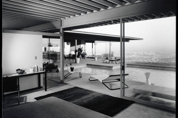 A black and white photo of a bedroom looking out to the outdoor swimming pool.