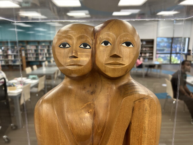Wood sculpture shows two faces.