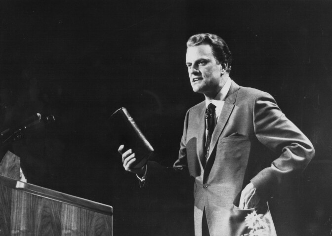 American evangelist Billy Graham, giving a speech on stage, circa 1970.