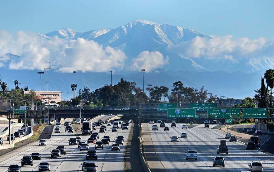 Snow on mountains behind a freeway.