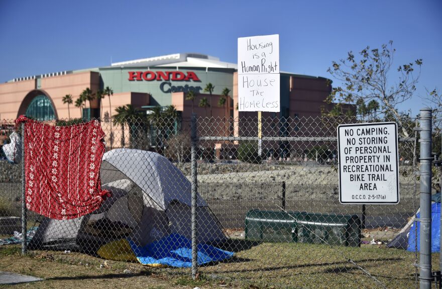 A sign reading "Housing is a Human Right, and House the Homeless" is placed on a fence near a tent housing the homeless near the Honda Center in Anaheim, California on January 23, 2018.
January 22 reports said authorities planned to clear out Orange County's largest homeless encampment with some 500 people living in tents. The Honda Center is home to the National Hockey League's Anaheim Ducks. / AFP PHOTO / FREDERIC J. BROWN        (Photo credit should read FREDERIC J. BROWN/AFP/Getty Images)