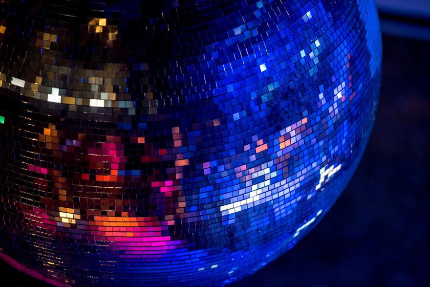 A disco ball glittering in blue and pink light.