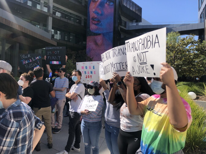 An image of a group of several protesters outside the Netflix office building. They were rallying against the new Dave Chappelle special and one protester held a sign that read, "Transphobia is not a joke."
