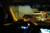 The driver of a car looks at an RV that appears to have an interior light on.