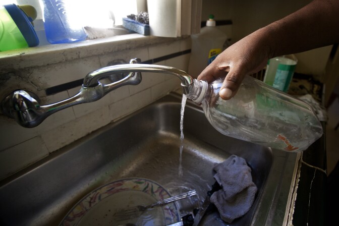 Maywood resident Robert Taylor fills a bottle with tap water in his home on Sept. 26.
