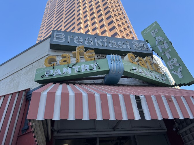 A sign that says Pantry Cafe above a striped awning.