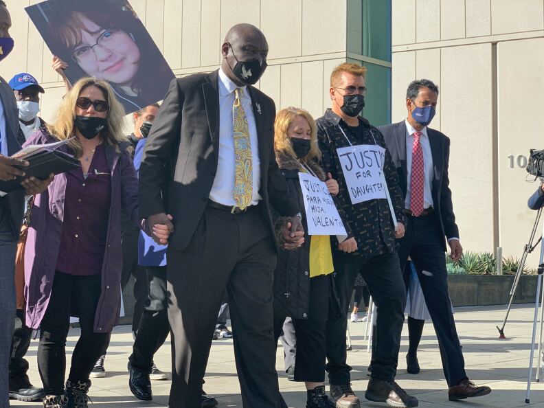 Valentina Orellana-Peralta's family and attorneys arrive at a news conference outside the LAPD headquarters holding hands. Orellana-Peralta’s mother, wears a sign that says, “Justicia para nuestra hija, Valentina.”