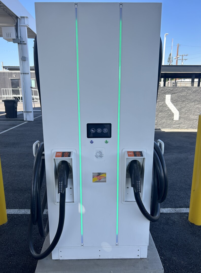 A rectangular, white electric vehicle charging station. Two lines run vertically lit green.