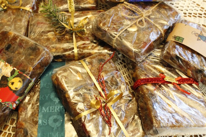 Brown fruit cake is wrapped with clear paper. Festive ribbons are tied around the cakes. 