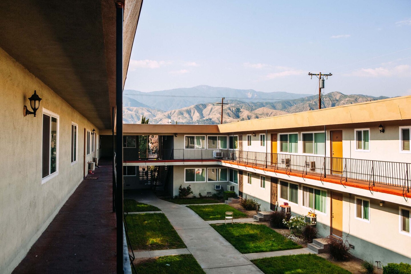A courtyard at the two-story River Glen Apartments in San Bernardino, California, the peaks of the San Bernardino mountains loom in the distance.