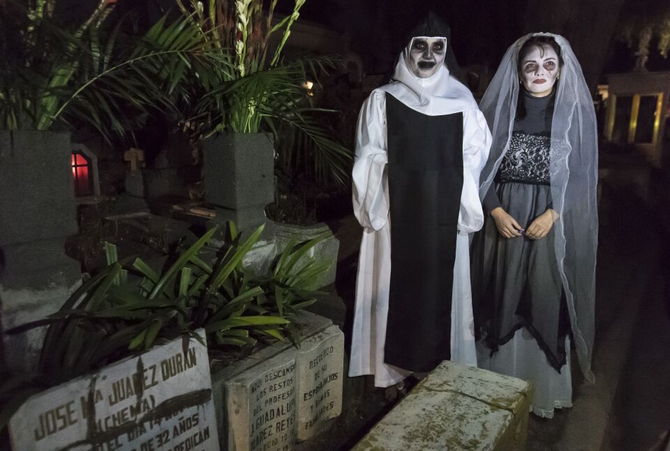 Tonatzin Cortes and Iyelitzin Cortes wear costumes during a visit to their relative's graves at the San Francisco Cemetery in Mexico City on November 1, 2016.