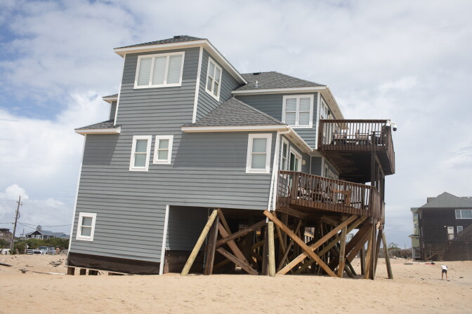 A house half-collapsed at a beach.