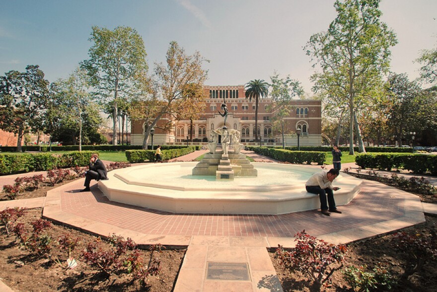 An image of a fountain at USC with some people sitting around it.