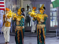 Image is there teenage boys celebrating Diwali by wearing traditional clothing while two boys hold lights the other boy  is holding a flag.