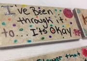 A young girl writes, "I've been through it too...it's okay," on a brick as away to deal with the experiences of forced prostitution at an empowerment conference for girls. 