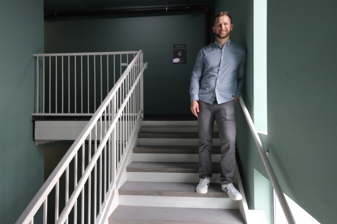 Culver City Council Member Bryan “Bubba” Fish — a man with light skin tone wearing a button–up shirt, chinos and sneakers — stands in the stairwell of his apartment building.