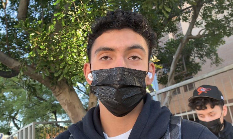 Close-up picture of face of teenage male in a black mask and hoodie.
