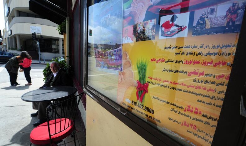 A man sits outside a cafe beneath where a sign which reads "Persian Square" overlooks a section Westwood Blvd. in Los Angeles, California, on March 15, 2012. A new reality TV show about the lavish lifestyles of rich young American-Iranians in Los Angeles has sparked angry claims it is degrading, and exploits the Persian community's image for ratings. The show is set in Tehrangeles, the name given to the West Coast metropolis's Persian community, where 20 percent of Beverly Hills' residents are of Iranian stock, said to be the biggest outside the Islamic Republic. AFP PHOTO/Frederic J. BROWN (Photo credit should read FREDERIC J. BROWN/AFP/Getty Images)