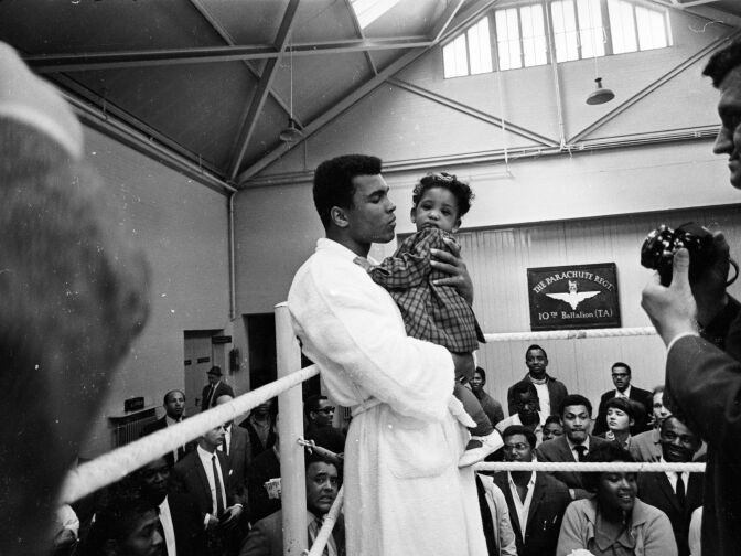 1966:  World heavyweight boxing champion Muhammad Ali meets eight-month-old Maria Morin during a training session at the Territorial Army Gymnasium at White City, London. Ali was training for his fight against British champion Henry Cooper at Arsenal's Highbury Stadium, London on May 2.