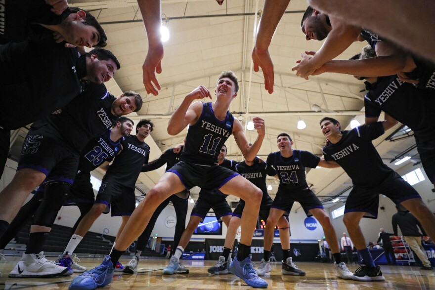 Ryan Turell stands in the center of Yeshiva basketball player locked arm-in-arm.