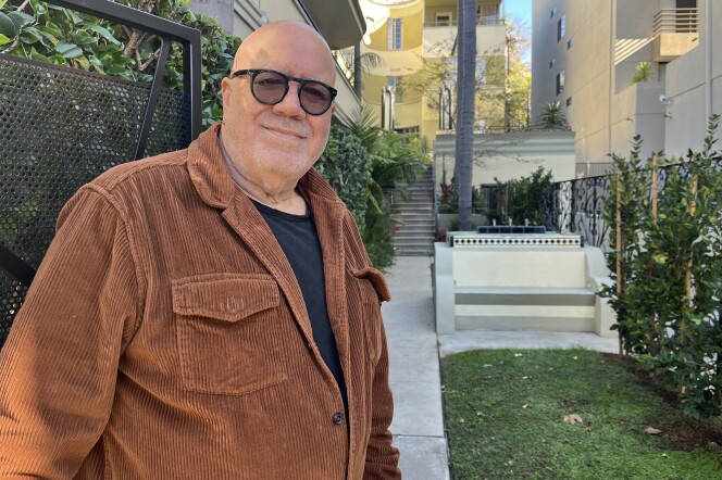 Dave Goldstein, a man with light skin tone, stands at the gate to one of his properties, a 1930s Streamline Moderne building in Hancock Park where John F. Kennedy once lived.  