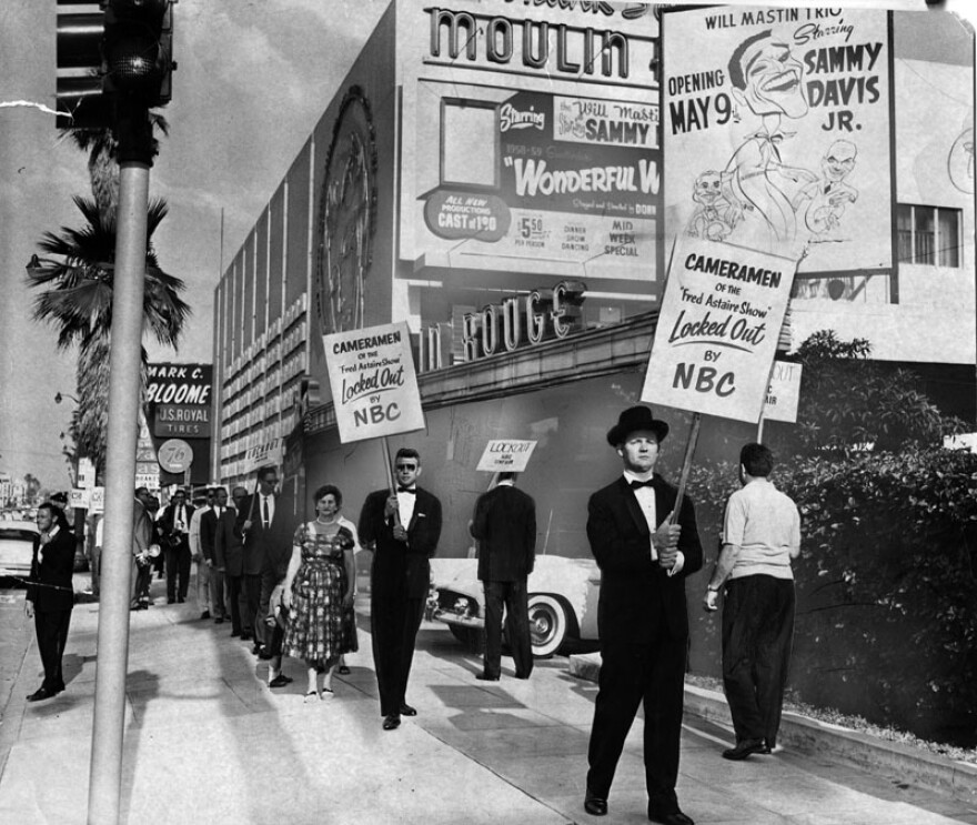 Picketers in a dispute with NBC ringed the Emmy Awards site on May 7, 1959. Two of them carry signs identifying them as "Cameramen of the Fred Astaire Show" — and they knew the affair was formal and dressed appropriately.