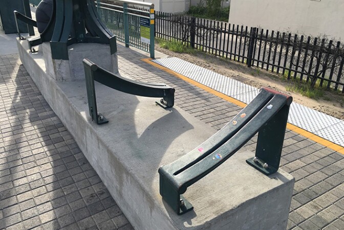 A bench that has multiple slanted dividers that allows only one person to sit on each section.