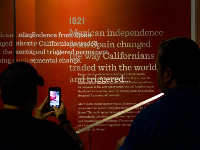 Museum patrons photograph a sword in the Becoming L.A. exhibit that represents a time between the Spanish Mission Era and the Mexican Rancho Era.