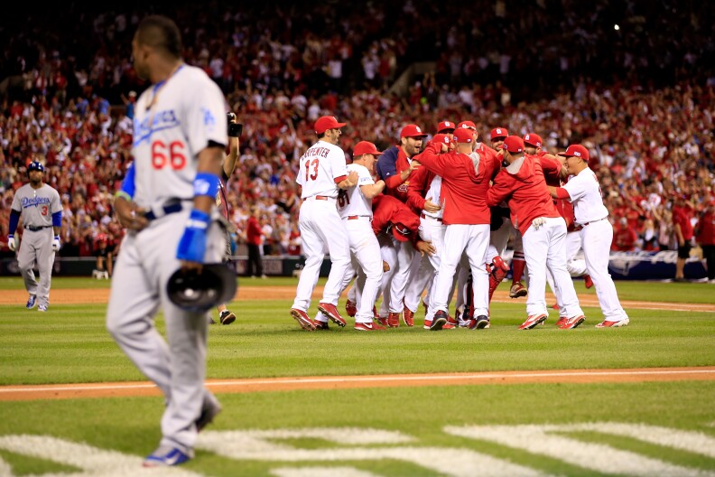 ST LOUIS, MO - OCTOBER 07:  The St. Louis Cardinals celebrate after defeating the Los Angeles Dodgers as Yasiel Puig #66 of the Los Angeles Dodgers walks off the field in Game Four of the National League Divison Series at Busch Stadium on October 7, 2014 in St Louis, Missouri.  (Photo by Jamie Squire/Getty Images)