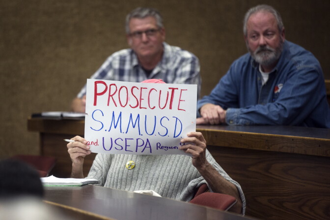 An attendee holds a sign during a question and answer session at the town hall meeting on toxic PCBs inside Malibu public schools at Pepperdine Law School.