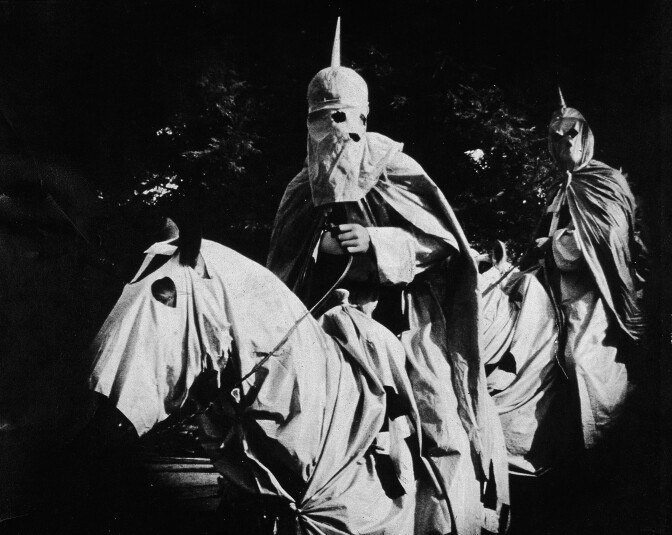 Actors costumed in the full regalia of the Ku Klux Klan ride on horses at night in a still from 'The Birth of a Nation,' the first-ever feature-length film, directed by D. W. Griffith, 1914. (Photo by Hulton Archive/Getty Images)