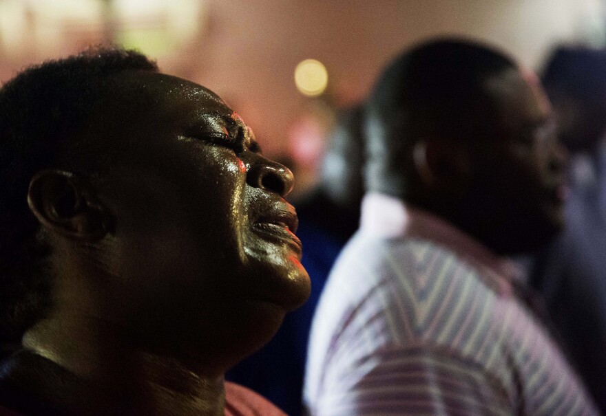 Lisa Doctor joins a prayer circle early Thursday, June 18, 2015, down the street from Emanuel AME Church following a shooting Wednesday night in Charleston, S.C. A white man opened fire during a prayer meeting inside the historic black church, killing multiple people, including the pastor, in an assault that authorities described as a hate crime. (AP Photo/David Goldman)
