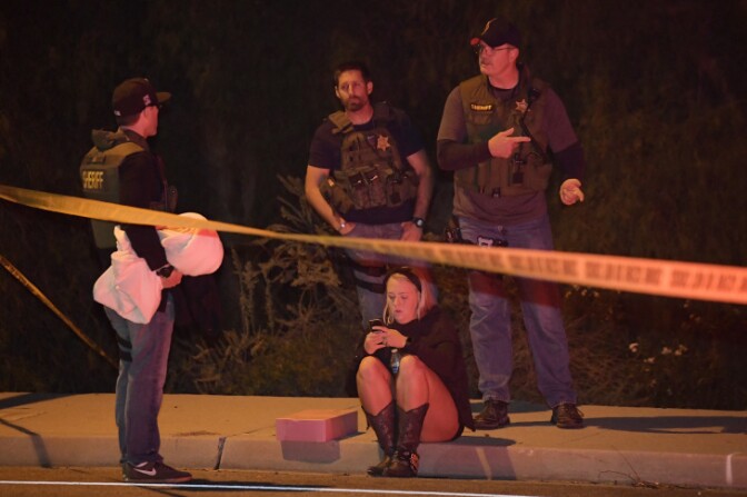 Sheriff's deputies speak to a potential witness as they stand near the scene Thursday, Nov. 8, 2018, in Thousand Oaks, Calif. where a gunman opened fire Wednesday inside a country dance bar crowded with hundreds of people on "college night," wounding 11 people including a deputy who rushed to the scene. Ventura County sheriff's spokesman says gunman is dead inside the bar. (AP Photo/Mark J. Terrill)