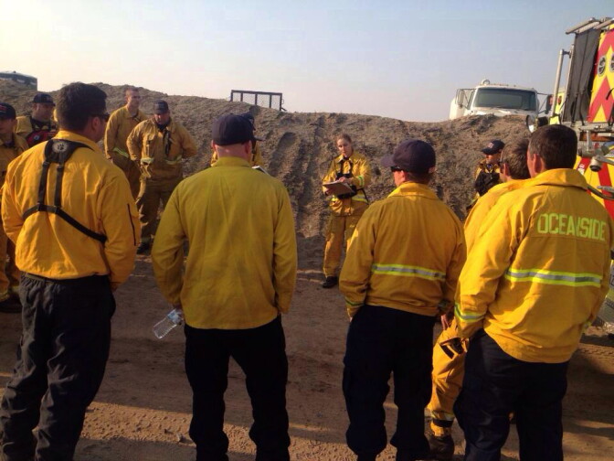 A battalion chief briefs San Diego firefighters deployed to help with the Highway Fire burning in Riverside County.