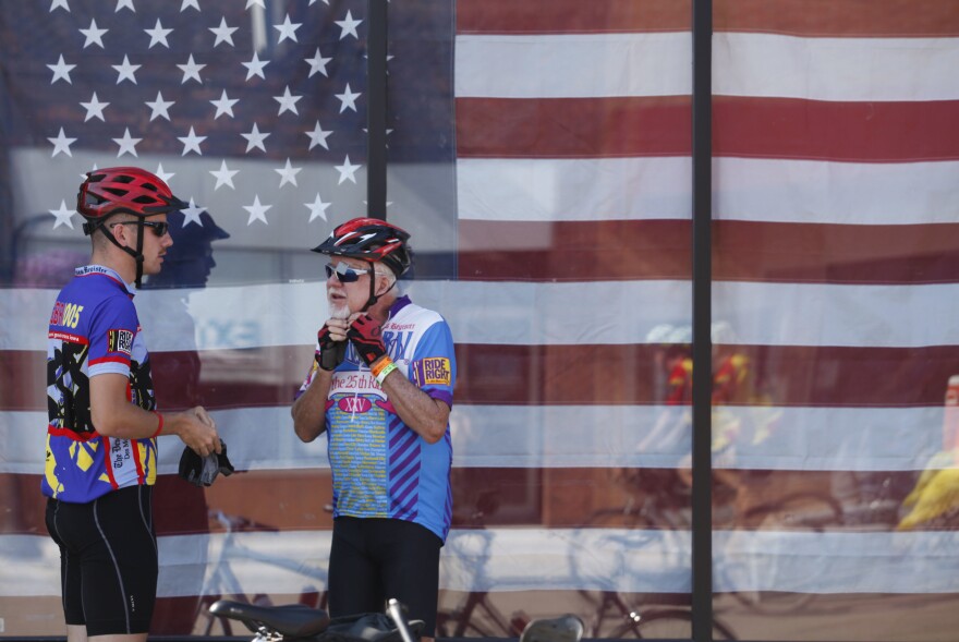 Gary Burger, 75, of West Des Moines, Iowa, puts on his helmet as he and his grandson, 21-year-old Aaron Burger of Cedar Falls, Iowa, get ready to get back on the road Wednesday, July 27, during a pit stop in Algona, Iowa. Gary Burger said he was riding with his three grandchildren and his wife. "It's just a lot of fun and gives us a chance to talk," he said.