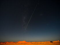 A bright white line is shown shooting down to earth against the night sky. 