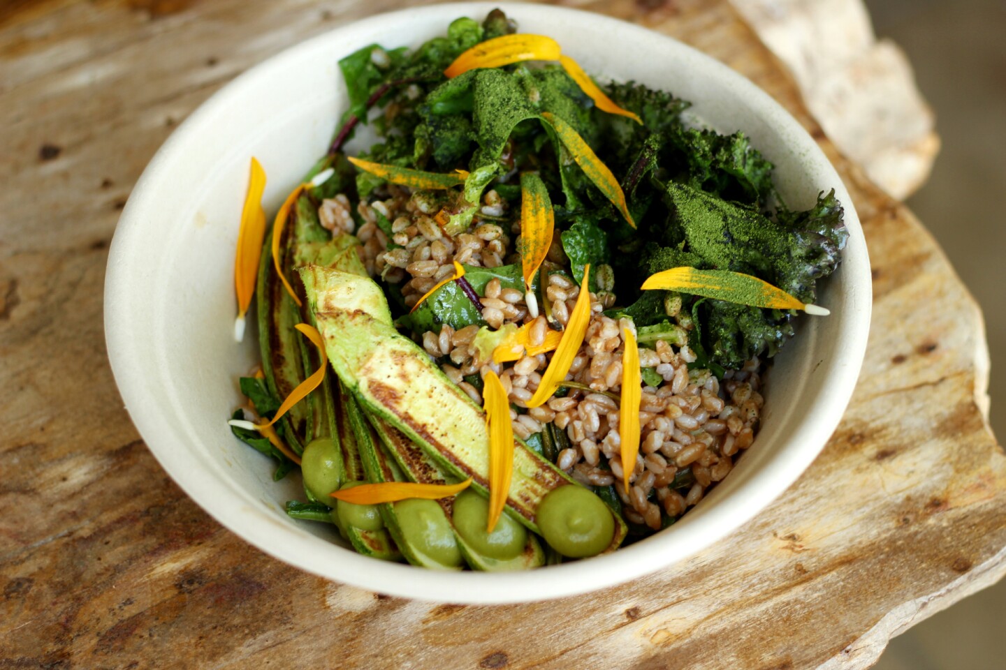 a bowl of cooked faro with seared zuchhini and greens.