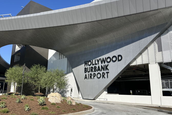A wide view of the new Hollywood Burbank Airport sign that's connected to a large rounded overhang across the facility. 