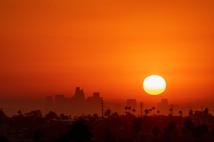 Sun rises in a red sky with the outline of skyscrapers visible