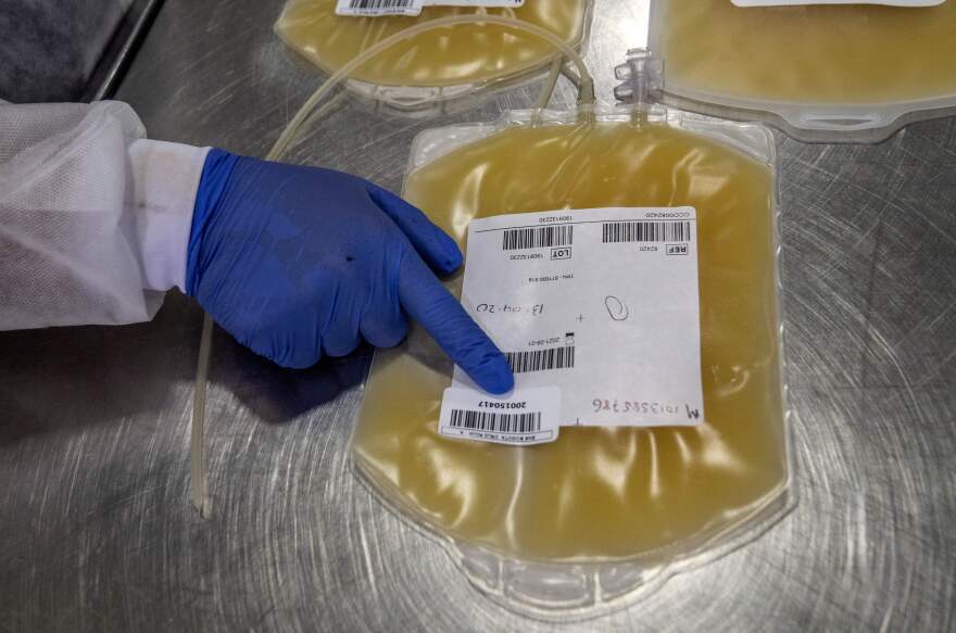 A gloved hand points to a bag of platelets