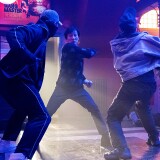 Man in sweater fighting two other men 