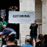 WASHINGTON, DC - AUGUST 15: Demonstrators gather outside of the condo of President Donald Trump donor and current U.S. Postmaster General  Louis Dejoy on August 15, 2020 in Washington, DC. The protests are in response to a recent statement by President Trump to withhold USPS funding that would ensure that the post office would be unable handle mail-in voting ballots for the upcoming 2020 Election. (Photo by Michael A. McCoy/Getty Images)