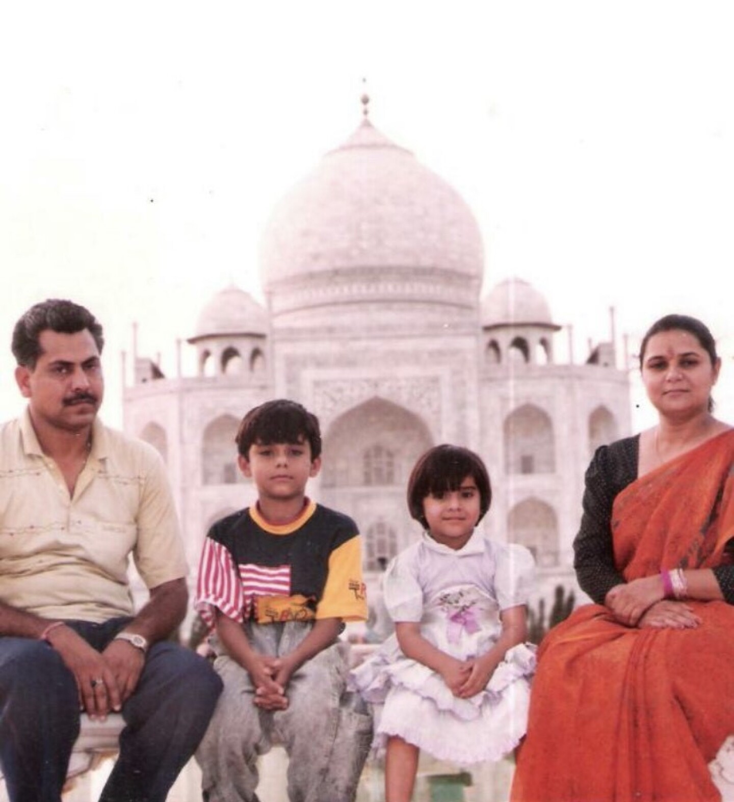 Nidhi Singh Rathore sits with her parents and brother with the Taj Mahal behind them.