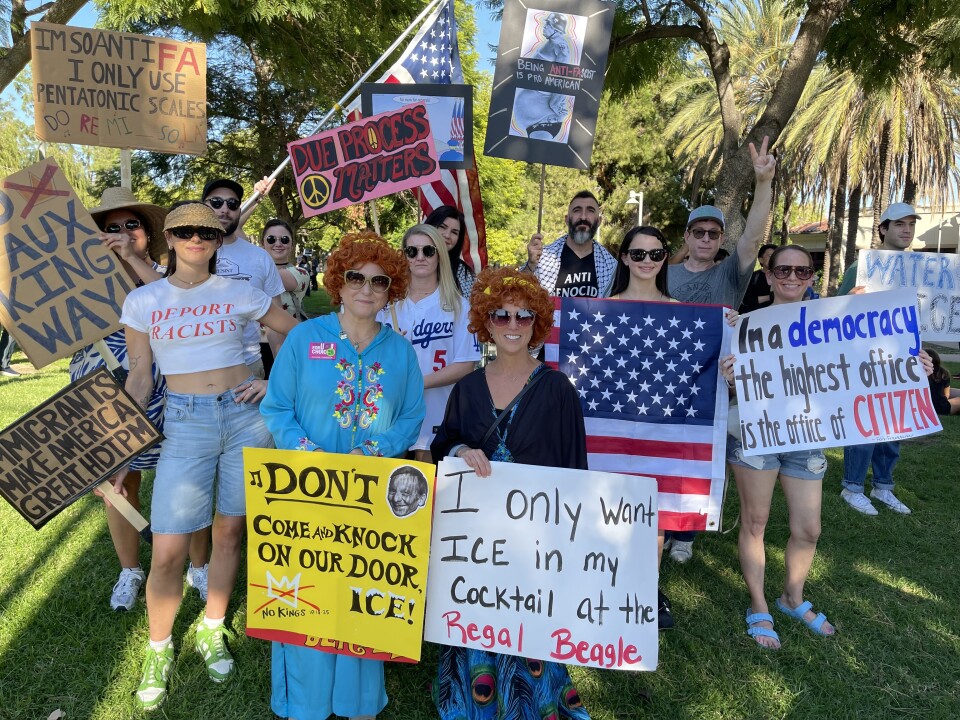People, including two in caftans, hold anti-Trump signs.