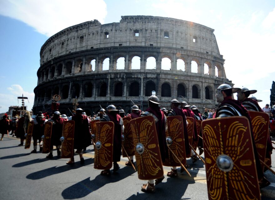 People dressed as soldiers of the ancient Rome march in front of the Coliseum during a parade to celebrate the anniversary of the legendary foundation of the city of Rome.