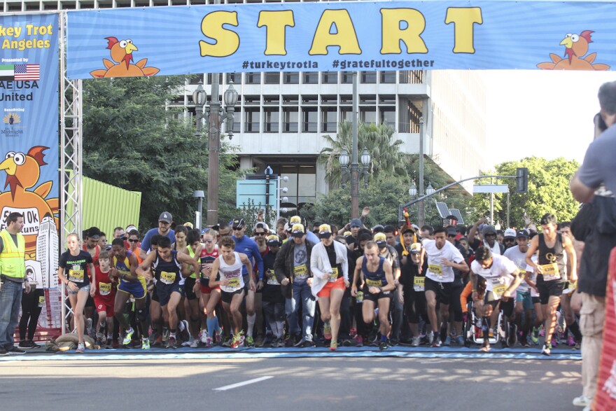 a bunch of runners race away from the starting line of a race